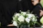 family at funeral in front of casket with bouquet of flowers